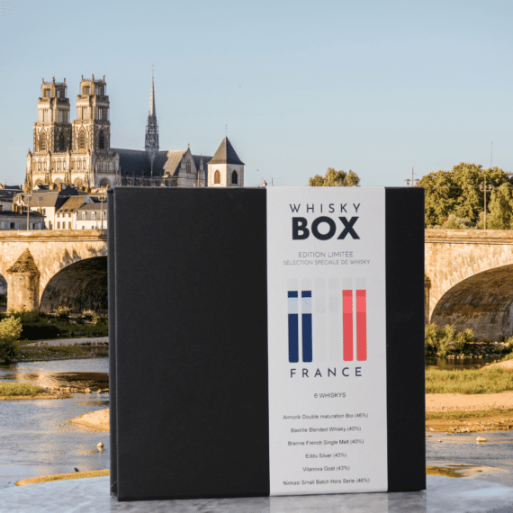 Coffret de dégustation de whiskys français devant une cathédrale et un village