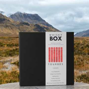 Coffret de dégustation de whiskys tourbés devant un paysage écossais